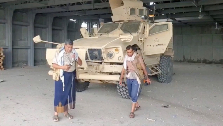 Un homme armé marche à côté d'un véhicule blindé, à Mocha