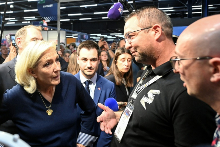 La cheffe de file du Rassemblement nationale, Marine Le Pen, parlent avec des exposants lors du congrès des sapeurs-pompiers au Mans, le 10 octobre 2025 dans la Sarthe ( AFP / JEAN-FRANCOIS MONIER )