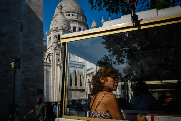 Une touriste à bord d'un petit train à Montmartre, le 5 août 2025 à Paris ( AFP / Dimitar DILKOFF )