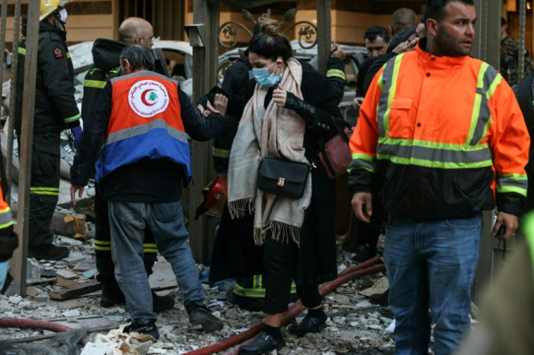 Une femme se fraie un chemin dans  les décombres d'un immeuble où des secouristes interviennent après une frappe aérienne israélienne dans le quartier d'Aïcha Bakkar à Beyrouth, le 11 mars 2026 au Liban ( AFP / IBRAHIM AMRO )