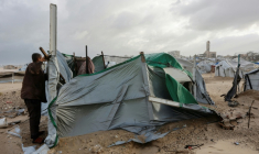 Un déplacé palestinien tente de réparer sa tente sous des vents violents sur une plage près de Gaza-ville, le 13 janvier 2026 ( AFP / Omar AL-QATTAA )