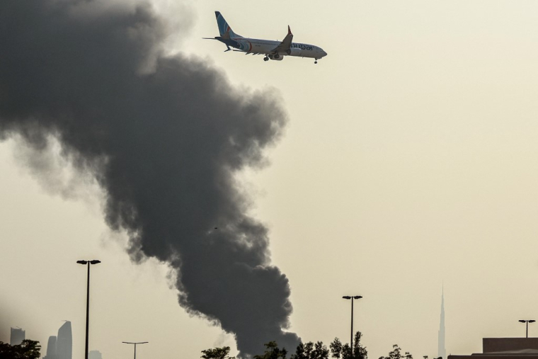 Un avion survole une panache de fumée provoqué par une frappe iranienne à Dubai, aux Émirats arabes unis, le 16 mars 2026. ( AFP / - )
