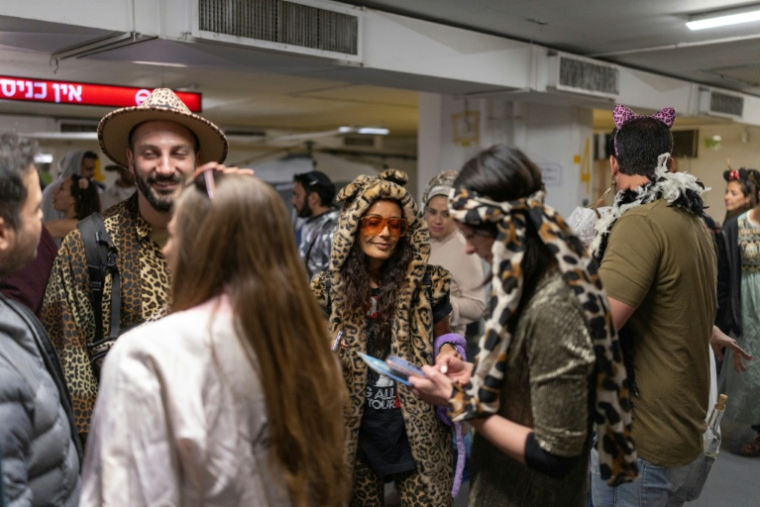 Des Israéliens costumés rassemblés dans un parking servant d'abri lors des célébrations de Pourim, à Tel-Aviv, le 2 mars 2026 ( AFP / Ilia YEFIMOVICH )