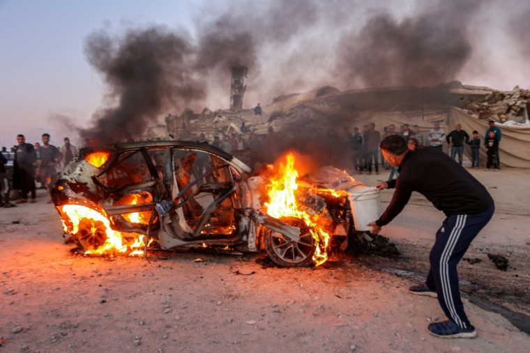 Un homme tient un seau d'eau pour éteindre les flammes du véhicule du journaliste palestinien Mohammed Wishah après une frappe de drone israélien dans le sud de la ville de Gaza, le 8 avril 2026 ( AFP / Omar AL-QATTAA )