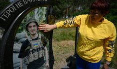 Nadia, 57 ans, mère du soldat ukrainien tué Andriï Doubnytsky, caresse son portrait sur sa tombe dans un cimetière du village de Stepantsi, dans la région de Tcherkassy, le 7 juillet 2026. ( AFP / Genya SAVILOV )