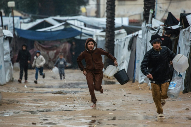 Des enfants courent dans un camp de tentes inondé à Deir el-Balah, dans le centre de la bande de Gaza, après le passage de la tempête Byron le 11 décembre 2025 ( AFP / BASHAR TALEB )