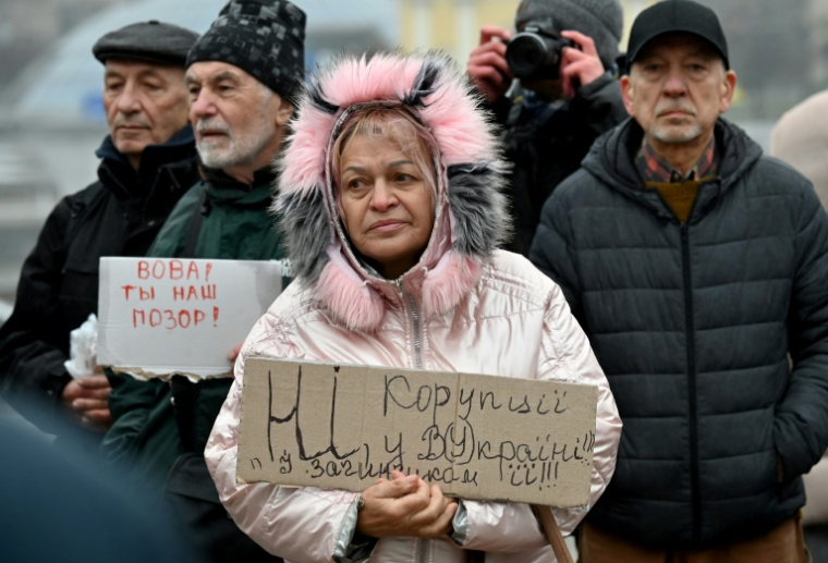 Des manifestants ukrainiens brandissent des pancartes anti-corruption visant le président Volodymyr Zelensky, à Kiev le 22 novembre 2025 ( AFP / Sergei SUPINSKY )