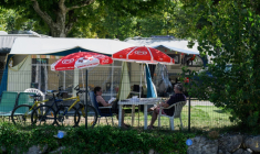 Des vacanciers assis à l'ombre dans un camping au Bourget-du-Lac, le 8 août 2025 en Savoie ( AFP / JEAN-PHILIPPE KSIAZEK )