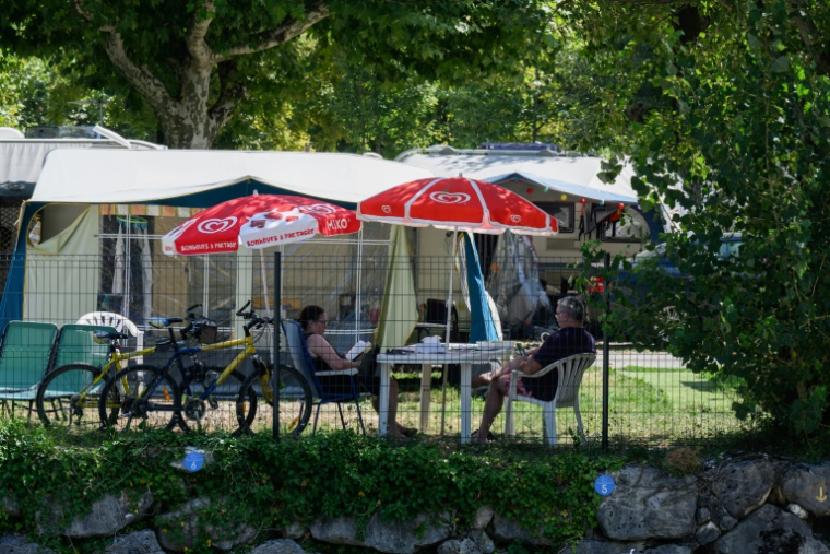 Des vacanciers assis à l'ombre dans un camping au Bourget-du-Lac, le 8 août 2025 en Savoie ( AFP / JEAN-PHILIPPE KSIAZEK )