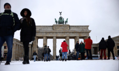Des passants devant la porte de Brandebourg, enneigée, à Berlin