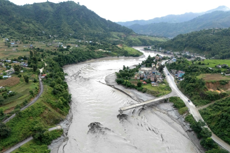 Un pont en partie détruit au-dessus de la rivière Trishuli après la crue destructrice dans l'Himalaya, le 30 août 2026 dans le district népalais de Dhading ( AFP / Manan VATSYAYANA )