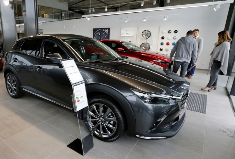 Des personnes regardent des voitures Mazda exposées dans une salle d'exposition d'un concessionnaire à Mérignac
