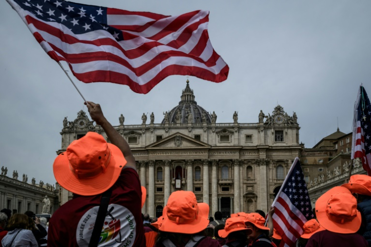 Des personnes se rassemblent avec des drapeaux américains sur la place Saint-Pierre, avec la basilique Saint-Pierre en arrière-plan, le jour où le pape Léon XIV dirige la prière Regina Caeli, au Vatican, le 11 mai 2025 ( AFP / JEFF PACHOUD )
