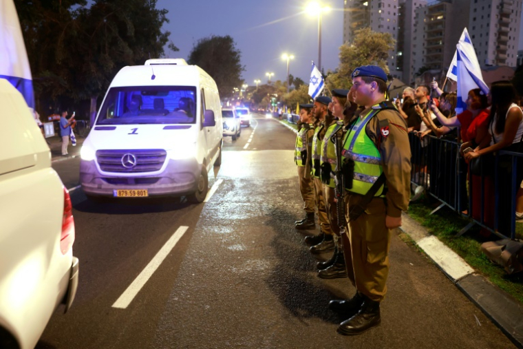 Des soldats israéliens saluent le passage d'une ambulance transportant un corps rendu par le Hamas, présumé être celui du lieutenant Hadar Goldin, tué en 2014 à Gaza, à Tel-Aviv, le 9 novembre 2025 ( AFP / Menahem Kahana )