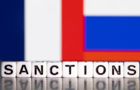 L'illustration montre des lettres disposées de manière à lire « Sanctions » devant les couleurs des drapeaux de la France et de la Russie.