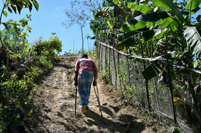 Ali Hossain, un Bangladais de 40 ans qui a perdu une jambe à cause d’une mine lorsqu'il ramassait du bois, regagne sa maison dans le district de Bandarban le 19 décembre 2025 ( AFP / Munir UZ ZAMAN )