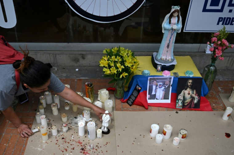 Une femme allume des bougies devant la clinique Santa Fe, où le sénateur Miguel Uribe est hospitalisé après avoir été blessé par balle lors d'un meeting politique, le 10 juin 2025 à Bogota, en Colombie ( AFP / Raul ARBOLEDA )