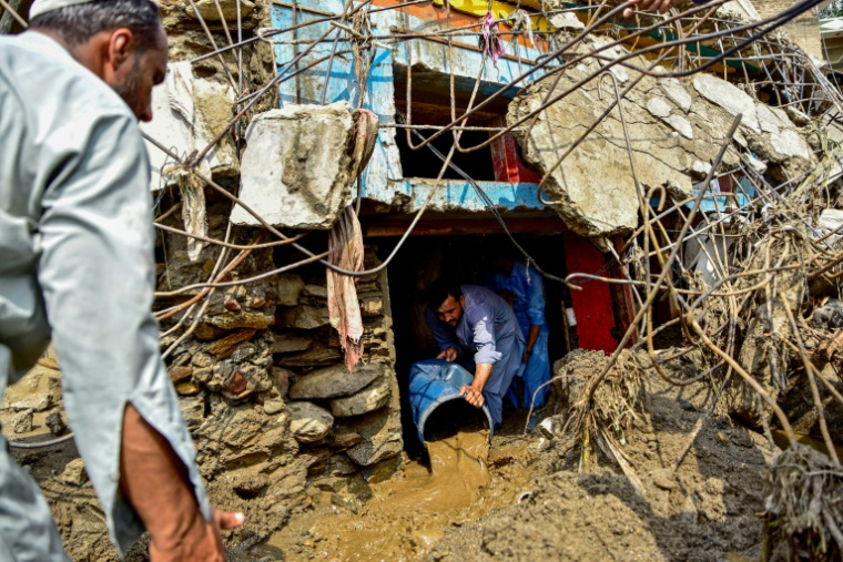 Un homme retire la boue de l'intérieur d'une maison après les crues subites dans la province montagneuse de Khyber Pakhtunkhwa au Pakistan le 16 août 2025 ( AFP / Hasham AHMED )