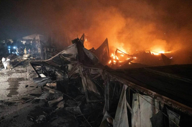 Des pompiers et des membres des forces de sécurité talibanes sur le site d'un hôpital pour toxicomanes détruit par des frappes aériennes pakistanaises, le 16 mars 2026 à Kaboul, en Afghanistan ( AFP / Wakil KOHSAR )
