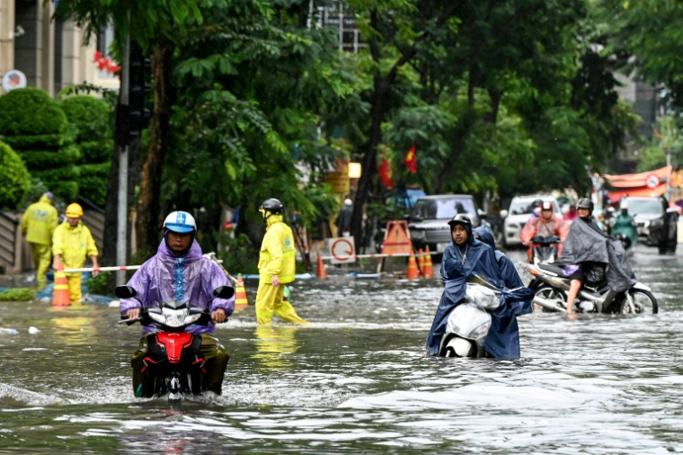 Des habitants dans une rue inondée à Hanoï après de fortes pluies causées par le typhon Matmo, le 7 octobre 2025 au Vietnam ( AFP / Nhac NGUYEN )