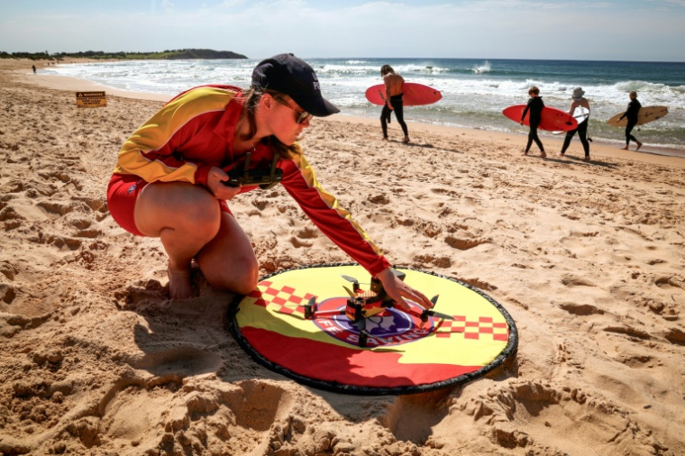La secouriste Eliza Heys vérifie un drone après son atterrissage sur une plage à Sydney, le 1er octobre 2025 ( AFP / DAVID GRAY )