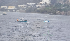 Un bateau de pêche s'approche d'un bateau pneumatique à moitié coulé qui transportait des migrants au large de l'île de Leros