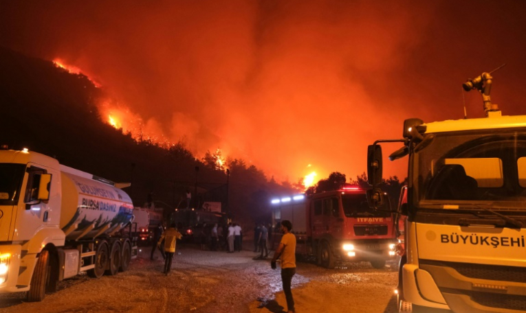 Les pompiers et des habitants tentent d'éteindre le feu dans une zone forestière du district de Gürsu, au nord-ouest de la Turquie, le 27 juillet ( AFP / ONUR YURTSEVER )