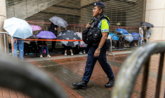 Un policier en patrouille devant la Cour de West Kowloon, à Hong Kong,  avant l'arrivée de Jimmy Lai pour son procès, le 18 août 2025 ( AFP / ISAAC LAWRENCE )