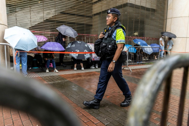 Un policier en patrouille devant la Cour de West Kowloon, à Hong Kong, avant l'arrivée de Jimmy Lai pour son procès, le 18 août 2025 ( AFP / ISAAC LAWRENCE )