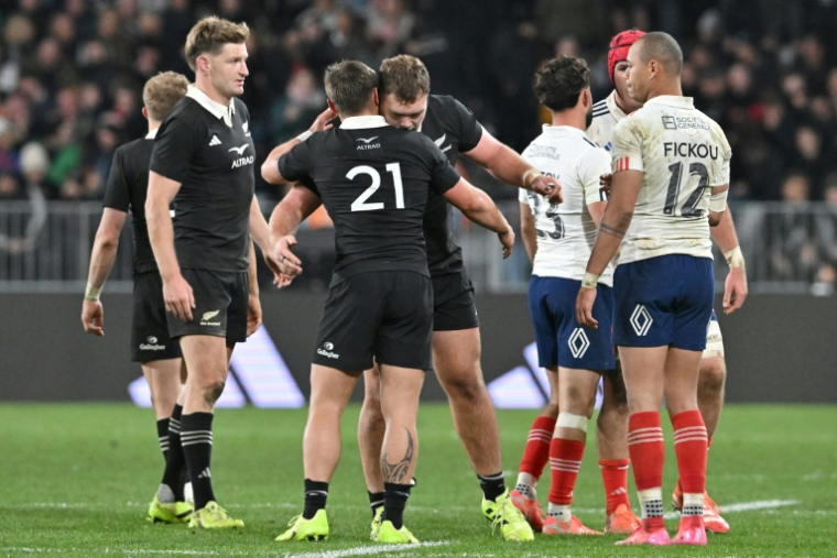 Le Français Gaël Fickou (d.) regarde les joueurs néo-zélandais célébrer leur victoire lors du premier test-match international de rugby entre la Nouvelle-Zélande et la France au stade Forsyth Barr de Dunedin, le 5 juillet 2025 ( AFP / Sanka Vidanagama )