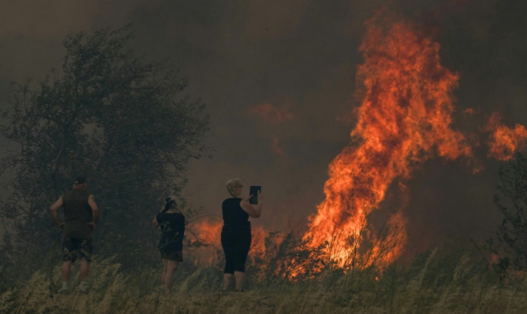 Une habitante filme un incendie à Tournissan, dans l'Aude, le 5 août 2025 ( AFP / IDRISS BIGOU-GILLES )