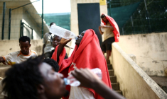 Des migrants boivent de l'eau devant le centre d'accueil de courte durée pour migrants de Ceuta, enclave espagnole en Afrique du Nord, le 1er août 2026 ( AFP / Henry Nicholls )