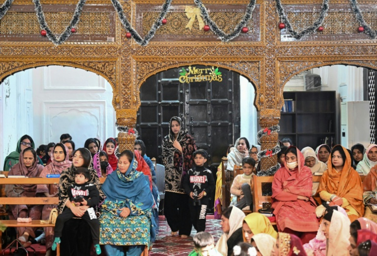 Natasha Zulfiqar (c), femme au foyer blessée avec ses parents dans un attentat meurtrier, arrive avec son fils pour prier à l'église All Saints de Peshawar à l'occasion de Noël, le 25 décembre 2025 au Pakistan ( AFP / Abdul MAJEED )