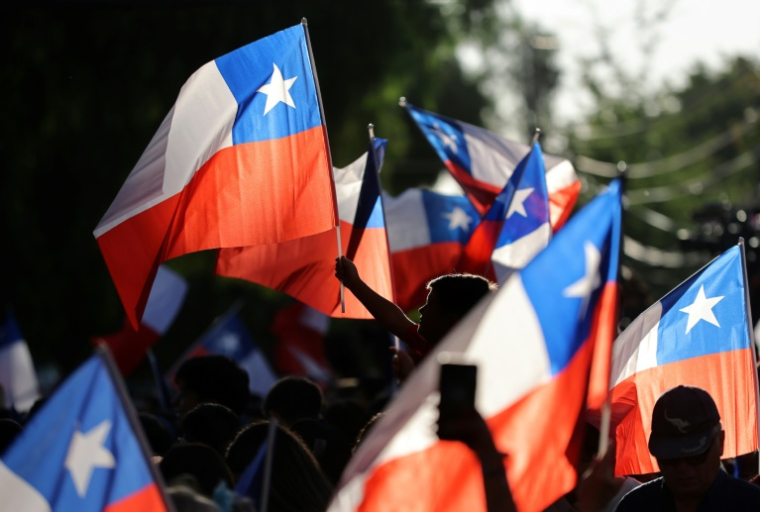 Des partisans du candidat à la présidentielle chilienne José Antonio Kast agitent des drapeaux nationaux après les premiers résultats du second tour de l’élection présidentielle à Santiago, le 14 décembre 2025 ( AFP / Javier TORRES )