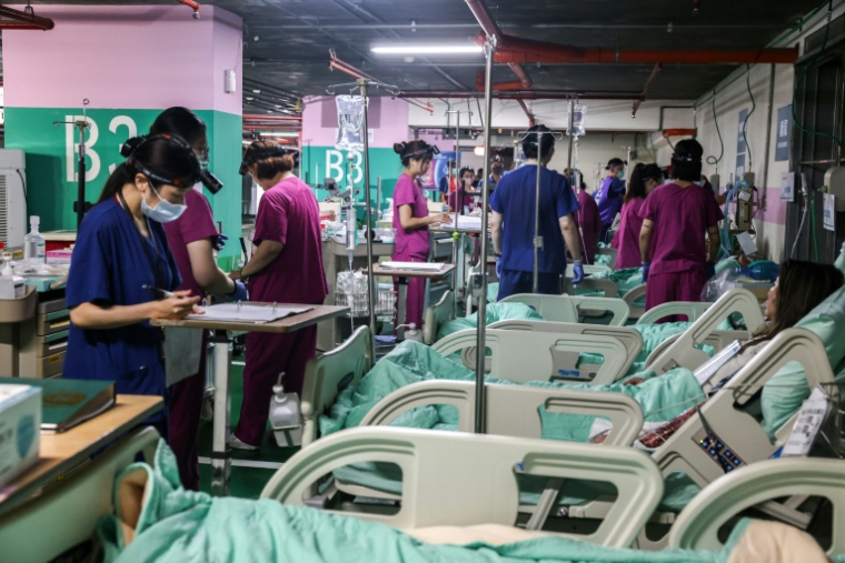 Du personnel médical soigne des patients blessés (simulés) dans une installation médicale souterraine lors d'un exercice de défe,se à New Taipei, le 13 août 2026 sur ll'île de Taïwan ( AFP / I-Hwa Cheng )