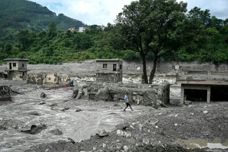 Un homme marche au milieu des décombres après la crue destructrice dans l'Himalaya, le 30 août 2026 à Trishuli, dans le district népalais de Nuwakot  ( AFP / Arun SANKAR )