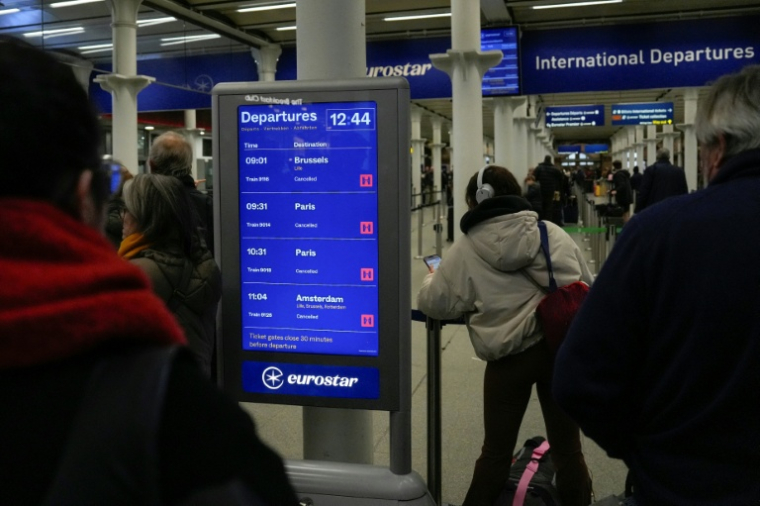 Des passagers regardent le tableau d'affichage montrant les trains annulés à la gare londonienne de St. Pancras après la suspension de toutes les liaisons Eurostar entre Paris et Londre le 30  décembre 2025 ( AFP / CARLOS JASSO )