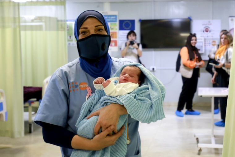 Une sage-femme tient un nouveau-né à la clinique de santé sexuelle et reproductive (SSR) soutenue par l'UNFPA dans le camp de Zaatari pour les réfugiés syriens près de la ville jordanienne de Mafraq, au nord de la capitale Amman, le 17 octobre 2022 ( AFP / Khalil MAZRAAWI )