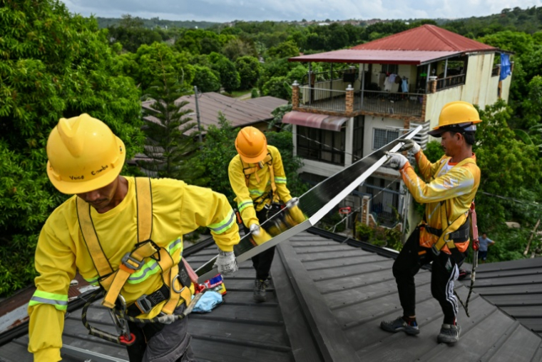 Des ouvriers installent des panneaux solaires sur un toit à Carmona, aux Philippines, le 9 juillet 2026 ( AFP / Jam STA ROSA )