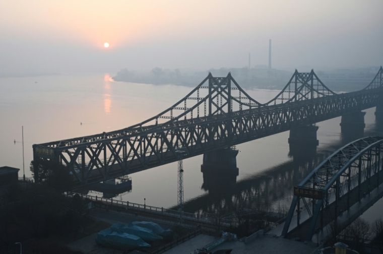 La ville nord-coréenne de Sinuiju, derrière le pont de l'Amitié sino-coréenne (g) et le pont brisé du fleuve Yalu (d), vue depuis la ville frontalière de Dandong, dans le nord-est de la Chine, le 26 mars 2026a's northeast Liaoning province on March 26, 2026. Passenger rail travel between China and North Korea resumed on March 12, after a pause of more than six years triggered by the COVID-19 outbreak. ( AFP / GREG BAKER )