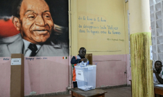 Un représentant de la commission électorale compte les votes de la présidentielle ivoirienne devant un tableau du premier président de Côte d'Ivoire, Félix Houphouët-Boigny, le 25 octobre 2025 à Abidjan ( AFP / Sia KAMBOU )