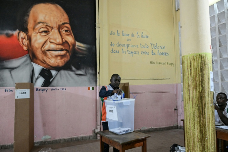 Un représentant de la commission électorale compte les votes de la présidentielle ivoirienne devant un tableau du premier président de Côte d'Ivoire, Félix Houphouët-Boigny, le 25 octobre 2025 à Abidjan ( AFP / Sia KAMBOU )