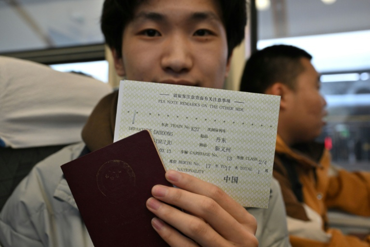 Un étudiant chinois montre son passeport et son billet de Dandong, en Chine, à Sinuiji, en Corée du Nord, à bord du train K27 en direction de Pyongyang, à la gare de Pékin, le 12 mars 2026 ( AFP / ADEK BERRY )