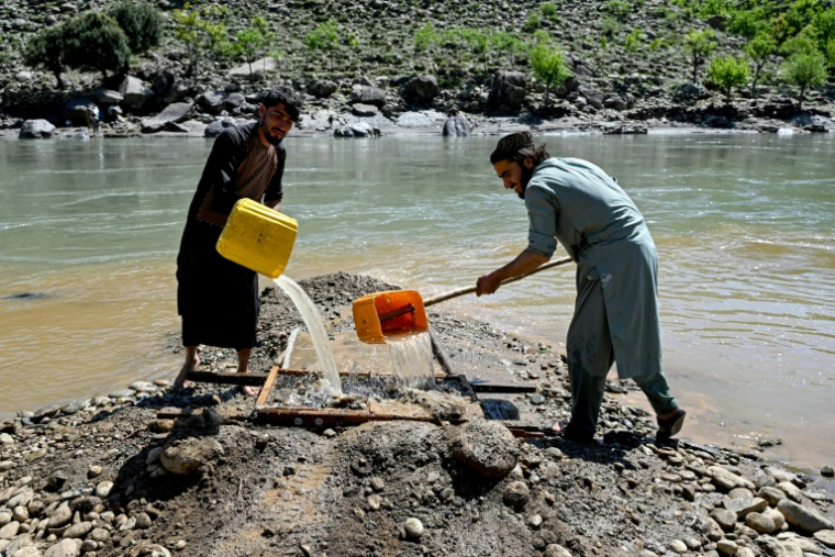 Des hommes versent de l'eau sur des tamis à la recherche de pépites d'or le long de la rivière Kunar, dans le district de Ghaziabad de la province de Kunar, le 13 avril 2026 en Afghanistan ( AFP / Wakil KOHSAR )