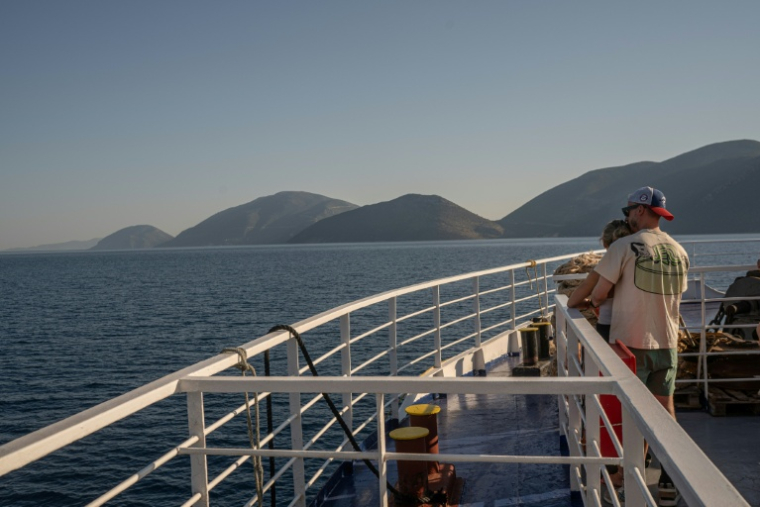 Des touristes sur le pont d'un ferry, le 3 août 2026, en route vers l'île grecque d'Ithaque, patrie d'Ulysse, héros de la mythologie grecque. ( AFP / Angelos TZORTZINIS )