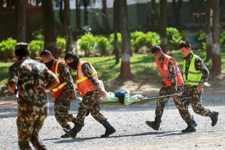 Des militaires népalais transportent une personne secourue, le 28 août 2026, à la suite des coulées de boue survenues à la frontière sino-népalaise l'avant veille ( AFP / PRABIN RANABHAT )