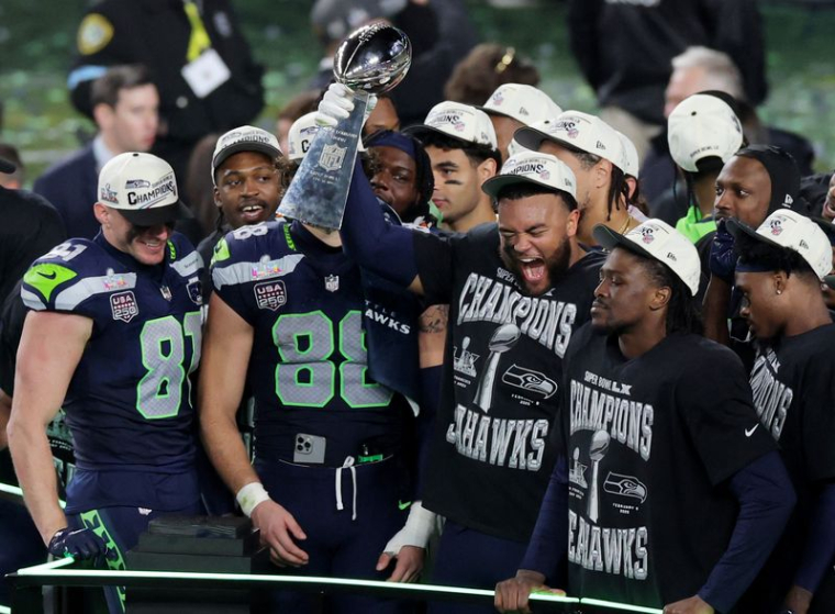 Les joueurs des Seattle Seahawks célèbrent avec le trophée sur le podium après avoir remporté le Super Bowl contre les New England Patriots
