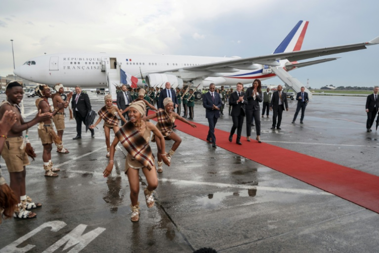 Le président français à son arrivée en Afrique du Sud, accueilli par des danseurs traditionnels, le 21 novembre 2025 ( AFP / Ludovic MARIN )