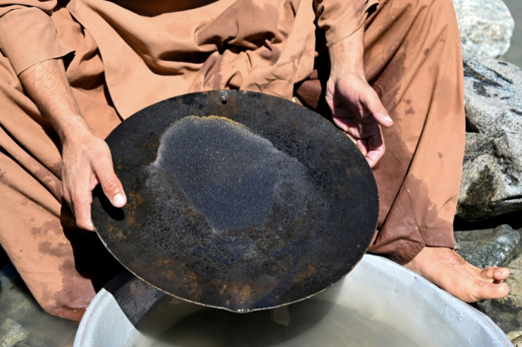 Un homme cherche de l'or en utilisant la technique traditionnelle de l'orpaillage, après avoir trié les pépites extraites des pierres de la montagne, provenant du lit de la rivière Kunar, dans le district de Naray de la province de Kunar, le 13 avril 2026 en Afghanistan ( AFP / Wakil KOHSAR )