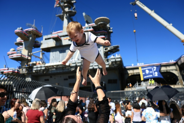 Des familles se réjouissent à l'arrivée du porte-avions américains USS Abraham Lincoln sur la base navale de San Diego, en Californie, le 8 octobre 2026 ( AFP / David Swanson )